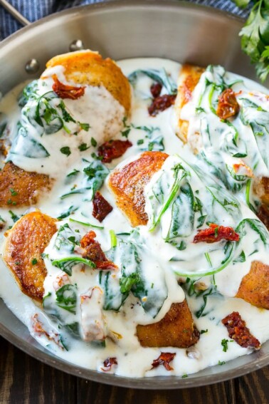 Sun dried tomato chicken covered in a creamy spinach sauce in a frying pan.