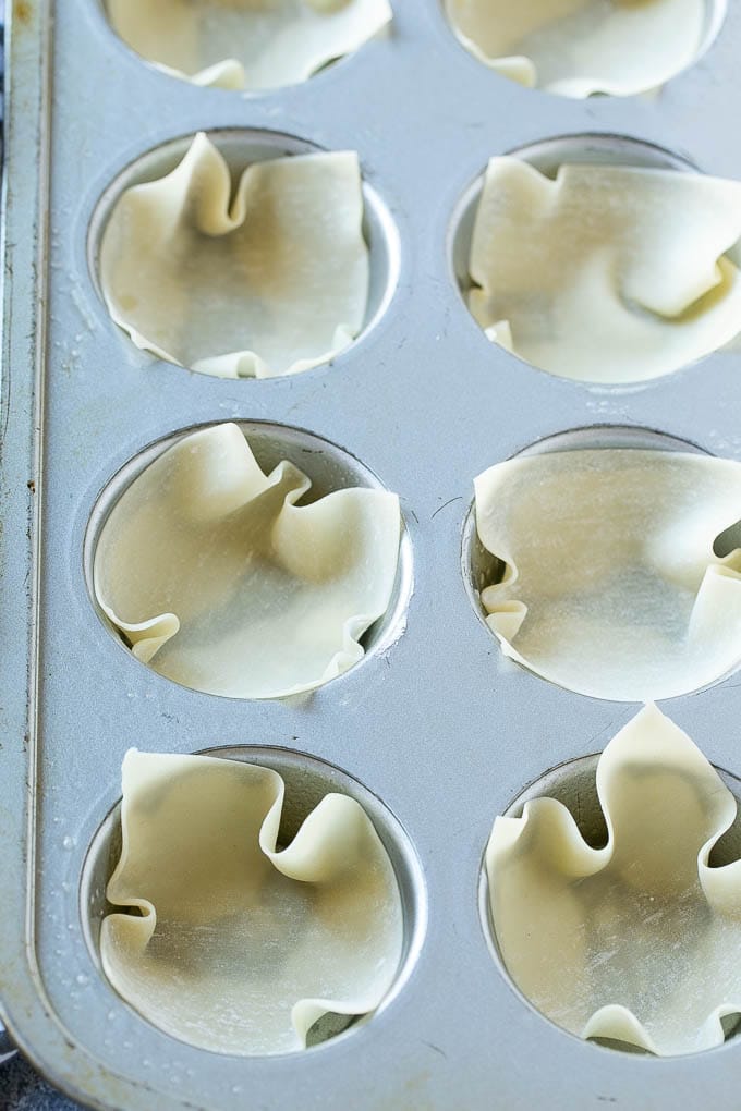 Wonton wrappers inside a muffin tin.