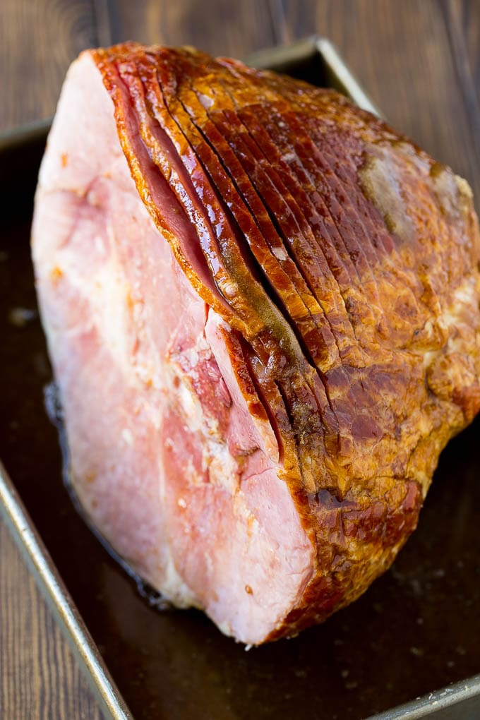 An uncooked spiral ham topped with coke and brown sugar.