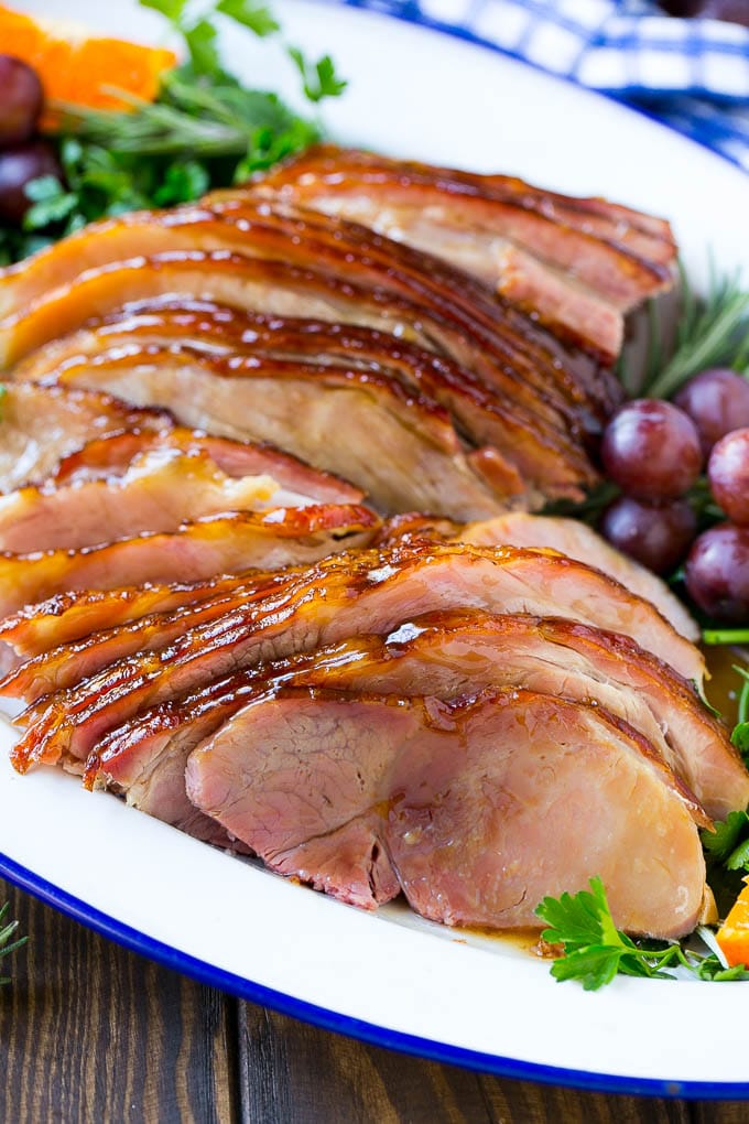 A platter of sliced coca cola ham with herbs.