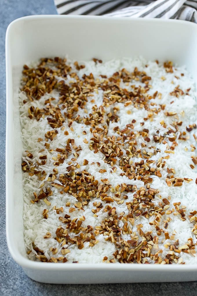 Coconut and pecans layered into a cake pan.