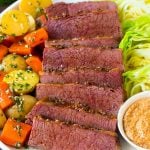 A platter of slow cooker corned beef, cabbage wedges, potatoes and carrots.