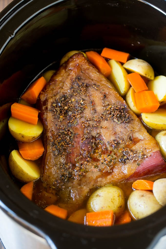 A corned beef brisket with potatoes and carrots in a slow cooker.