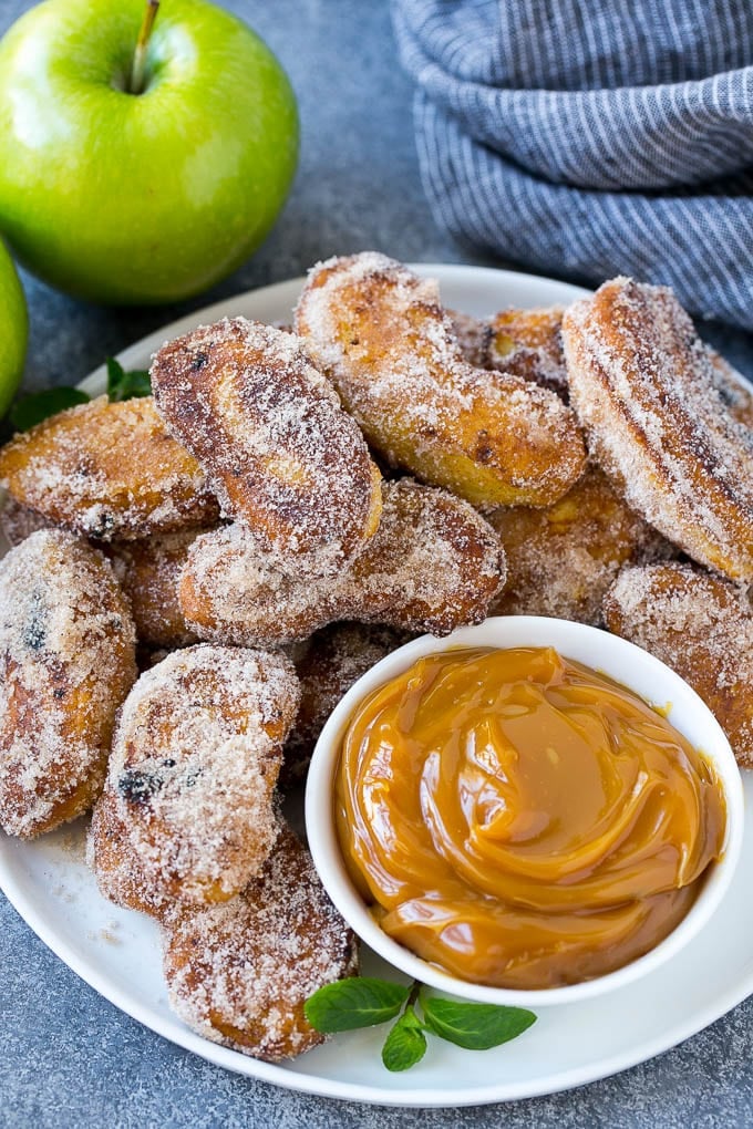 A pile of cinnamon sugar apple fries with caramel sauce for dipping.