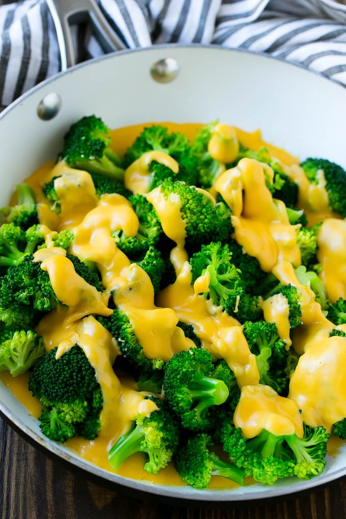 A pan of broccoli topped with cheese sauce.
