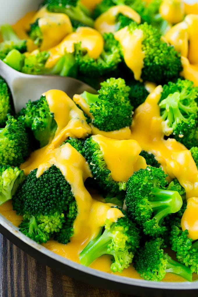 A pan of steamed broccoli smothered in melted cheese sauce.