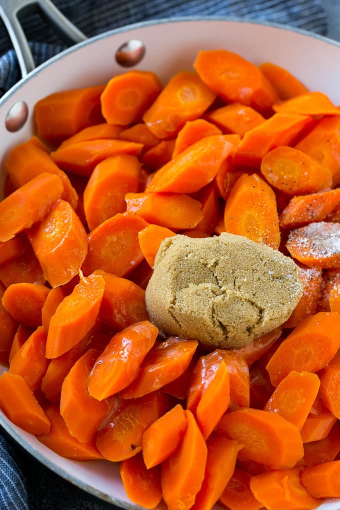 Sliced carrots with butter, brown sugar and seasonings in a pan.