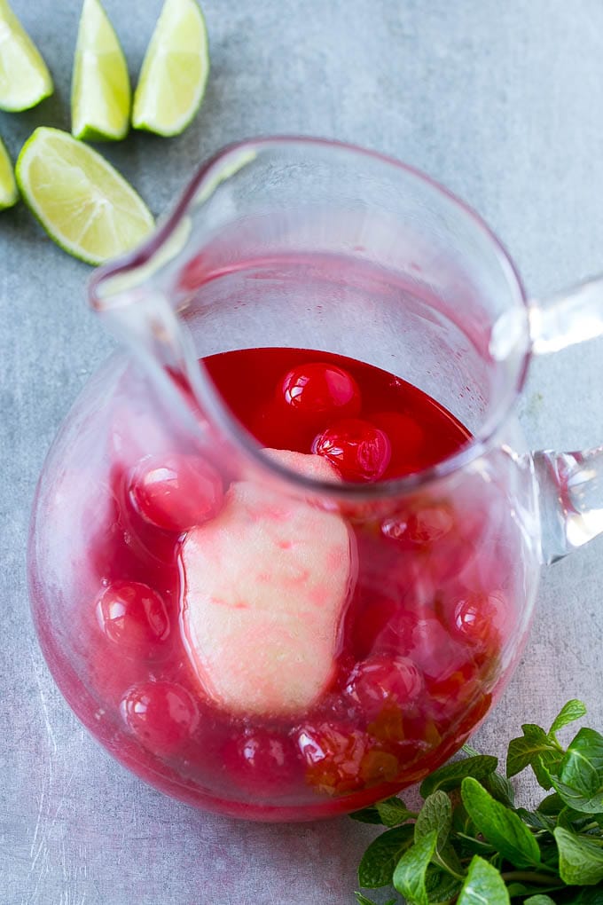 Limeade concentrate and maraschino cherries and juice in a pitcher.