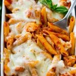 Chicken parmesan pasta in a baking dish topped with melted cheese and garnished with fresh basil.
