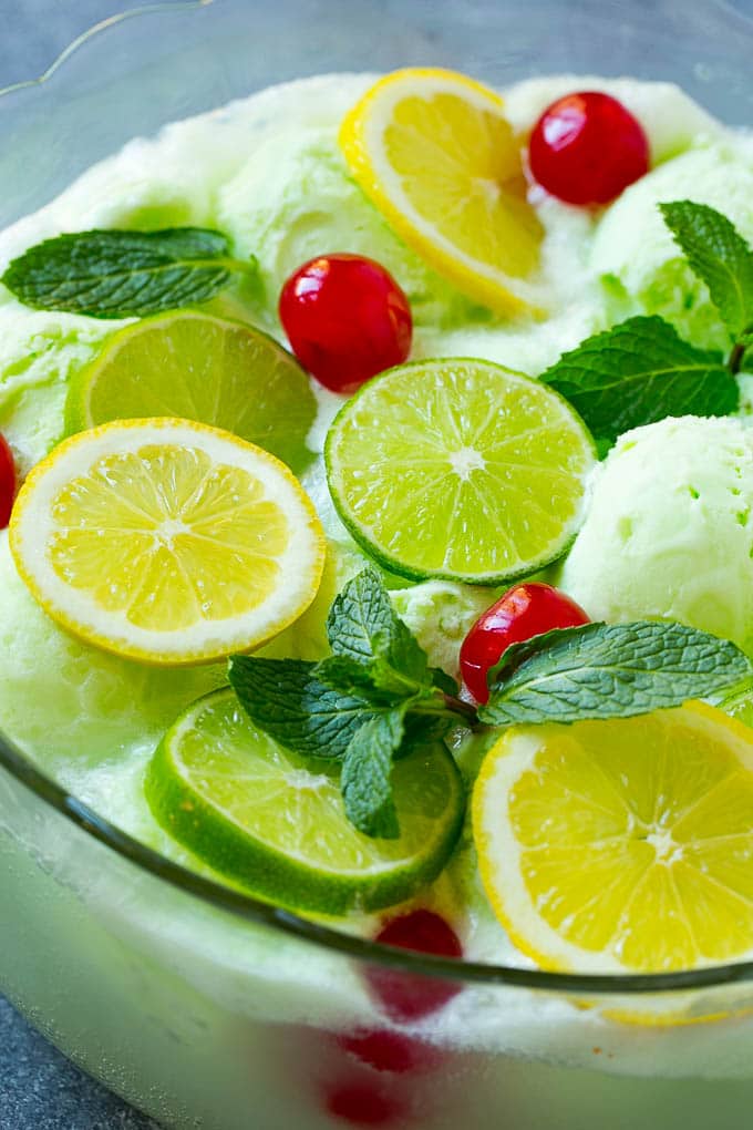 A close up of a bowl of sherbet punch garnished with citrus and mint.