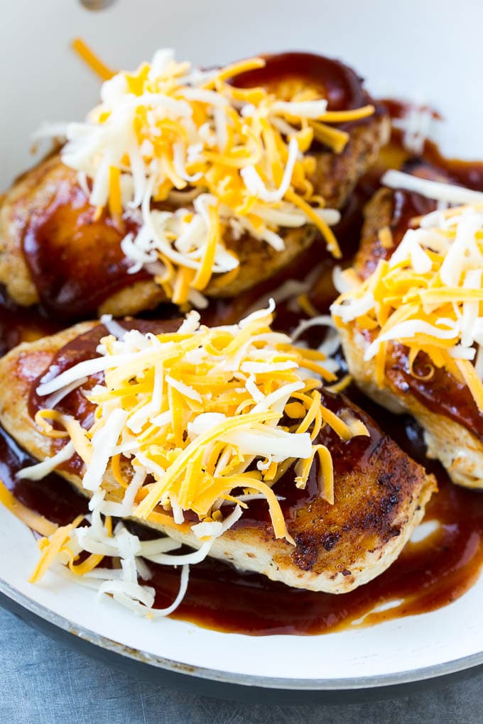 Barbecue chicken in a skillet, topped with shredded cheese.