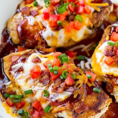 A skillet of Monterey chicken with seasoned cooked chicken breasts topped with barbecue sauce, two types of cheese and bacon.