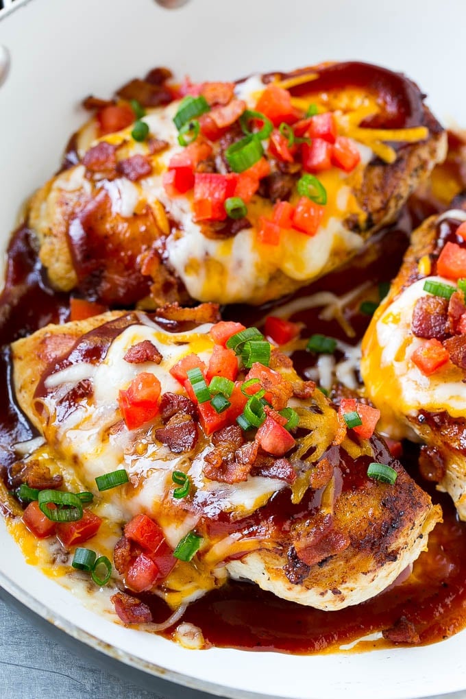 A skillet of Monterey chicken with seasoned cooked chicken breasts topped with barbecue sauce, two types of cheese and bacon.