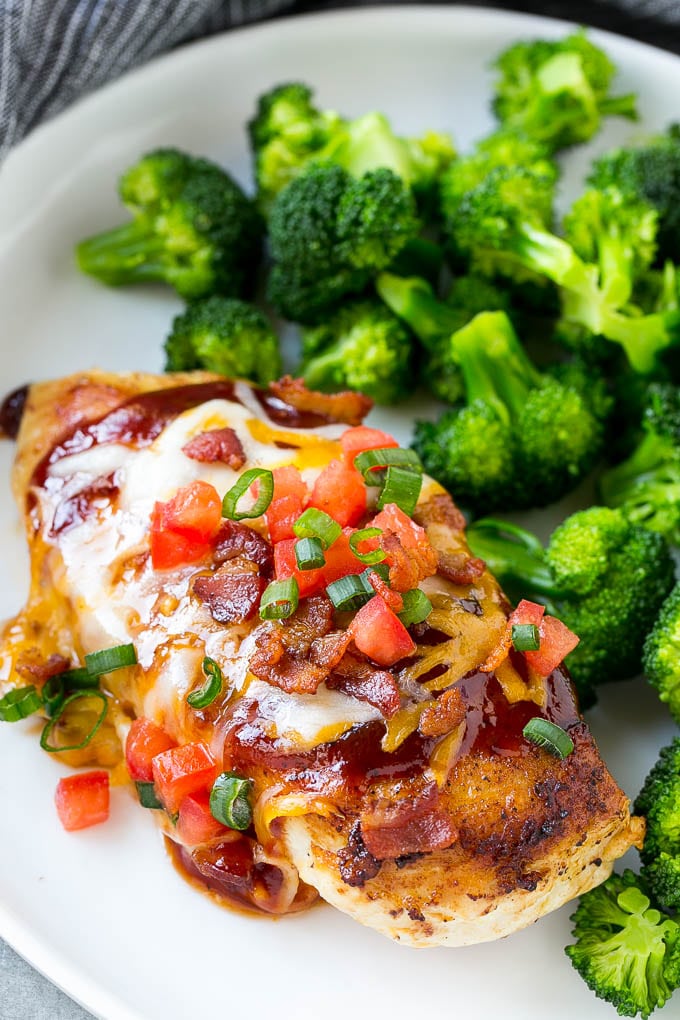 Monterey chicken covered in barbecue sauce, cheese, bacon and tomatoes, served with a side of broccoli.