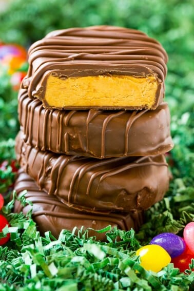 Peanut butter eggs stacked in a pile with one cut open.