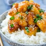 Slow cooker orange chicken served over a bowl of rice.