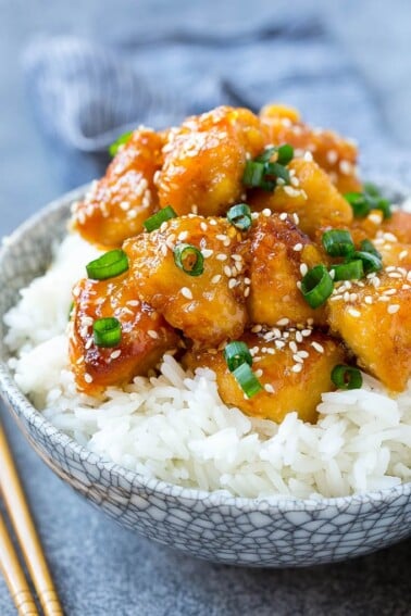 Slow cooker orange chicken served over a bowl of rice.