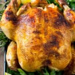 Slow cooker whole chicken with broiled crispy skin, garnished with lemon and herbs.