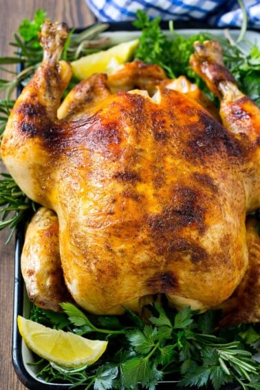 Slow cooker whole chicken with broiled crispy skin, garnished with lemon and herbs.