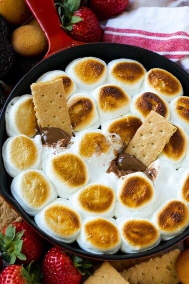 A skillet of s'mores dip with melted milk chocolate topped with toasted marshmallows.