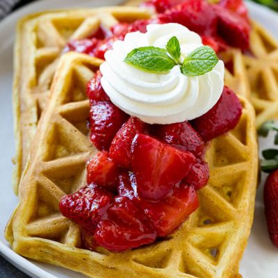 Strawberry waffles are homemade waffles topped with fresh strawberry sauce and whipped cream.