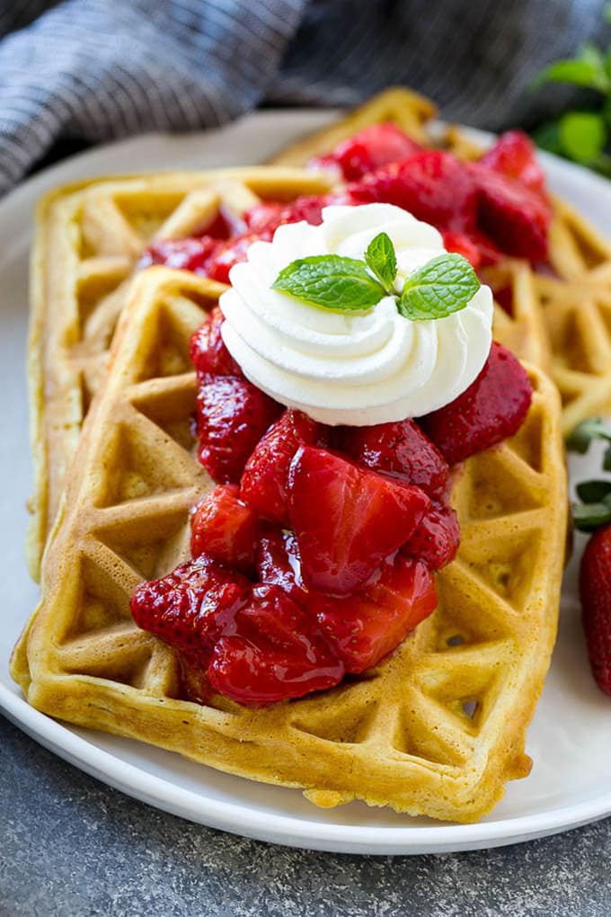 Strawberry waffles are homemade waffles topped with fresh strawberry sauce and whipped cream.