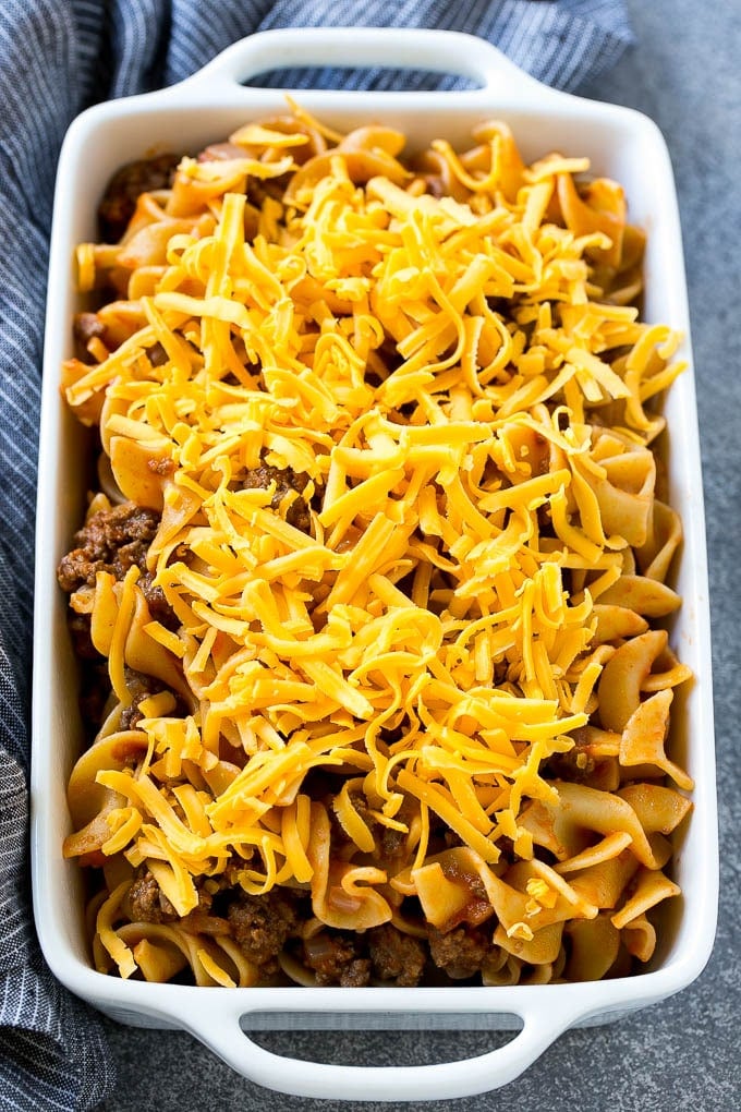 A pan of ground beef and egg noodles in tomato sauce, topped with shredded cheddar cheese.