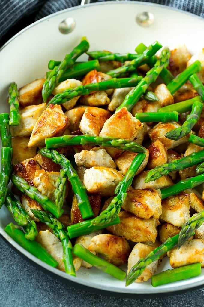 A skillet of seared chicken and asparagus.