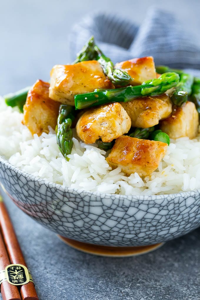 A bowl of chicken and asparagus stir fry served over steamed rice.