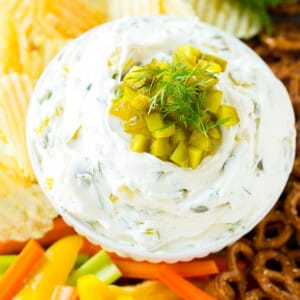 A bowl of dill pickle dip served with vegetables.