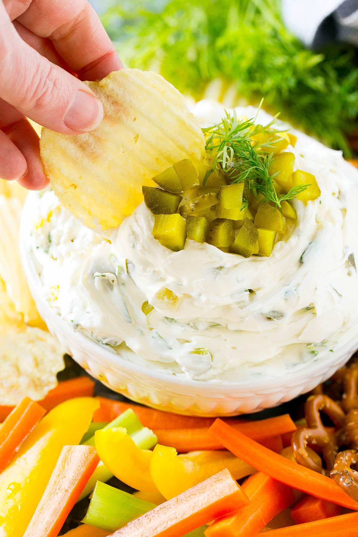 A chip scooping up a serving of dill pickle dip.