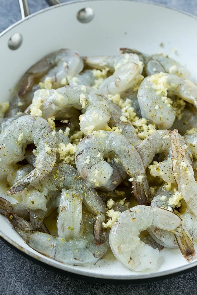 Raw shrimp in a skillet with minced garlic and butter.