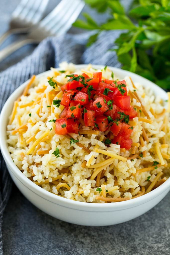 A bowl of homemade rice-a-roni topped with chopped tomatoes and herbs.