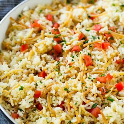 Homemade rice a roni topped with tomatoes and herbs, all in a skillet.