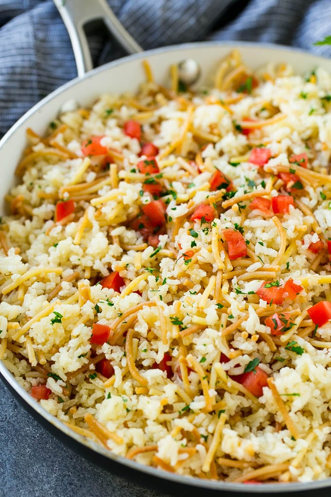 Homemade rice-a-roni topped with tomatoes and herbs, all in a skillet.
