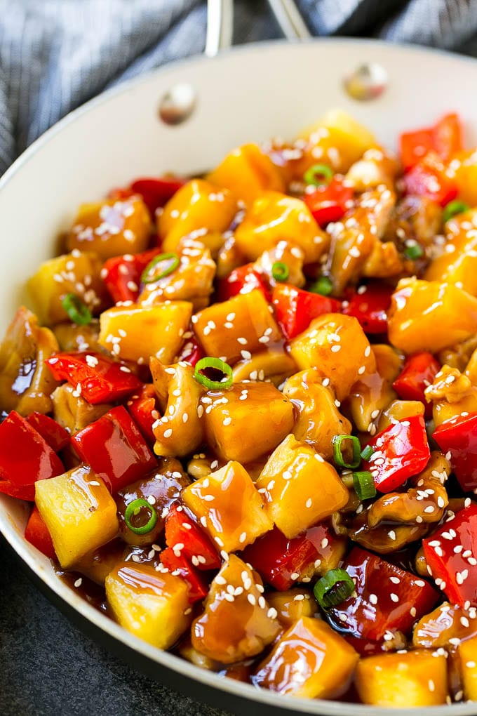 A skillet of pineapple chicken with chunks of chicken, pineapple and bell peppers..