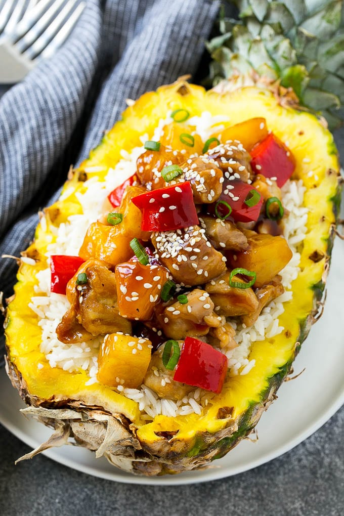Pineapple chicken stir fry over rice served inside half a pineapple.