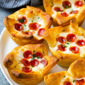 A plate of pizza muffins made with crescent roll dough, pizza sauce, melted cheese and mini pepperoni.
