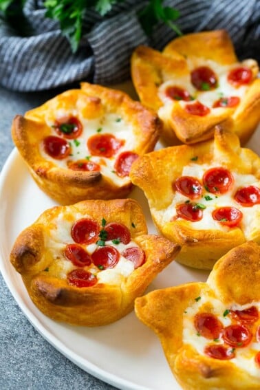 A plate of pizza muffins made with crescent roll dough, pizza sauce, melted cheese and mini pepperoni.