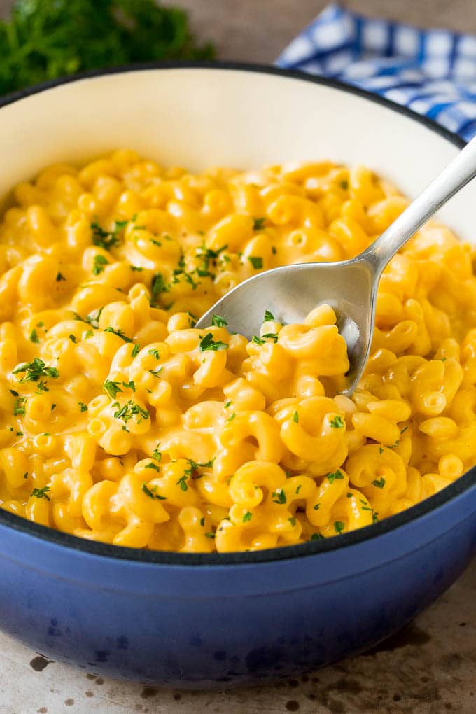 Stovetop mac and cheese in a blue pot with a serving spoon.