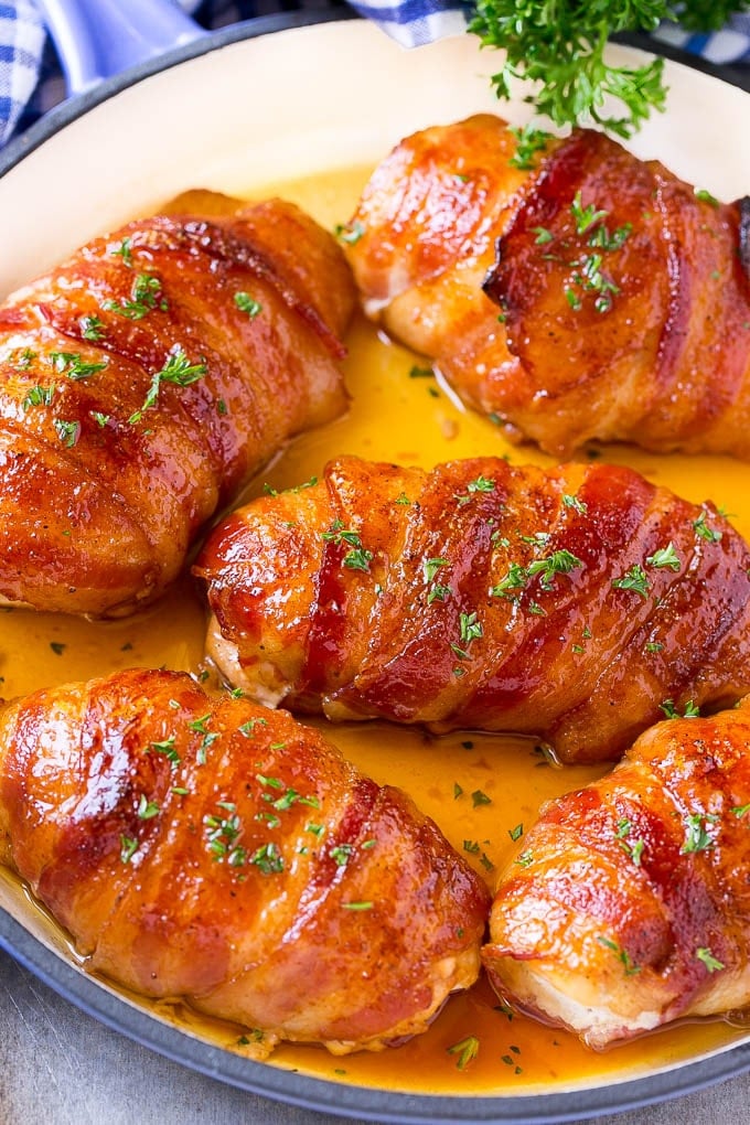 A pan of bacon wrapped chicken baked to golden brown and topped with parsley.