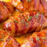 Bacon wrapped chicken breast with sauce in a skillet.