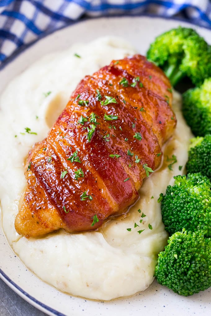 Bacon wrapped chicken served over mashed potatoes with broccoli on the side.