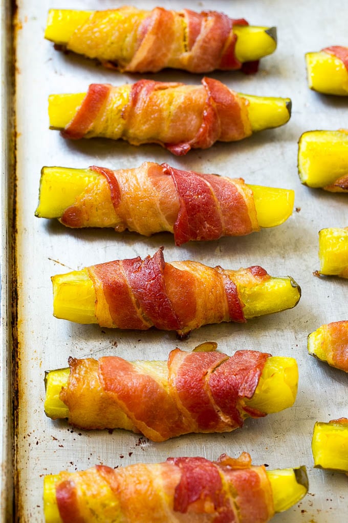 Crispy bacon wrapped pickle spears on a sheet pan.