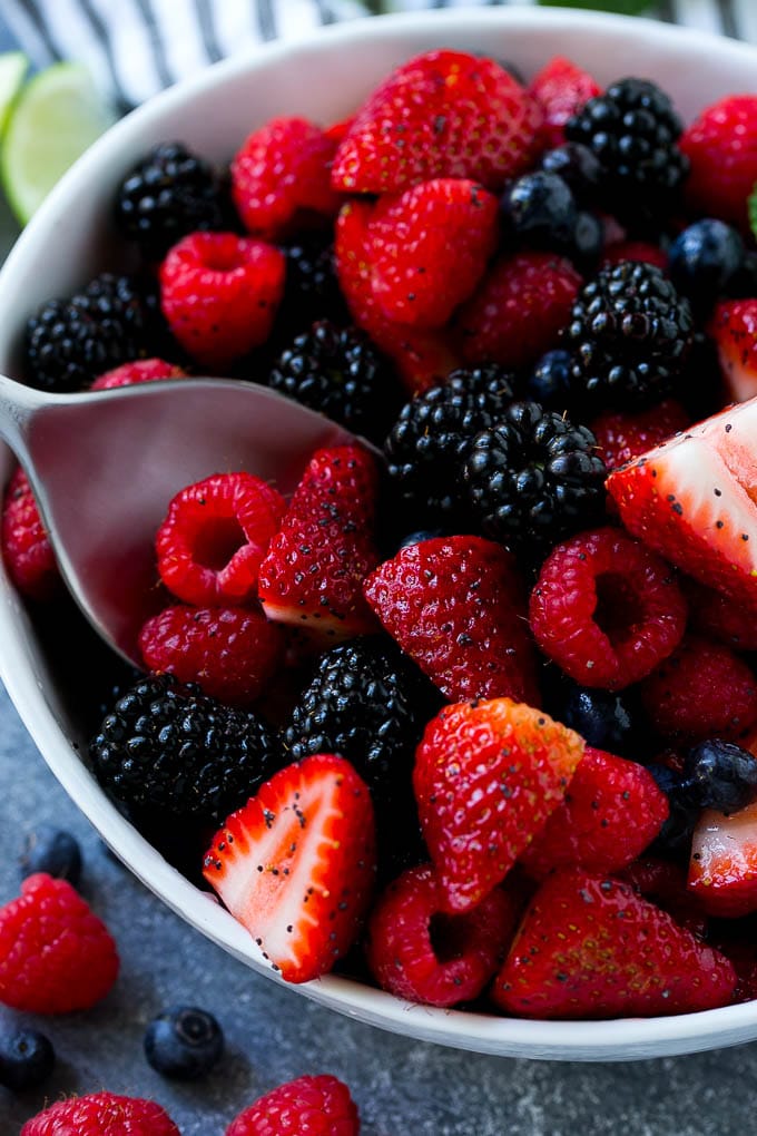 A bowl of berry fruit salad with a serving spoon in it.