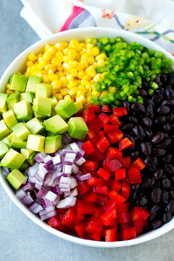 A bowl of beans, corn, diced red peppers, minced jalapeno, red onion and avocado.