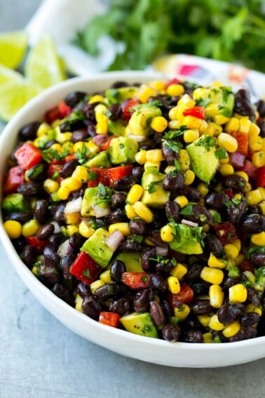 A bowl of black bean and corn salad loaded with avocado and red pepper, garnished with fresh cilantro.