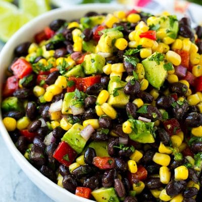 A bowl of black bean and corn salad loaded with avocado and red pepper, garnished with fresh cilantro.