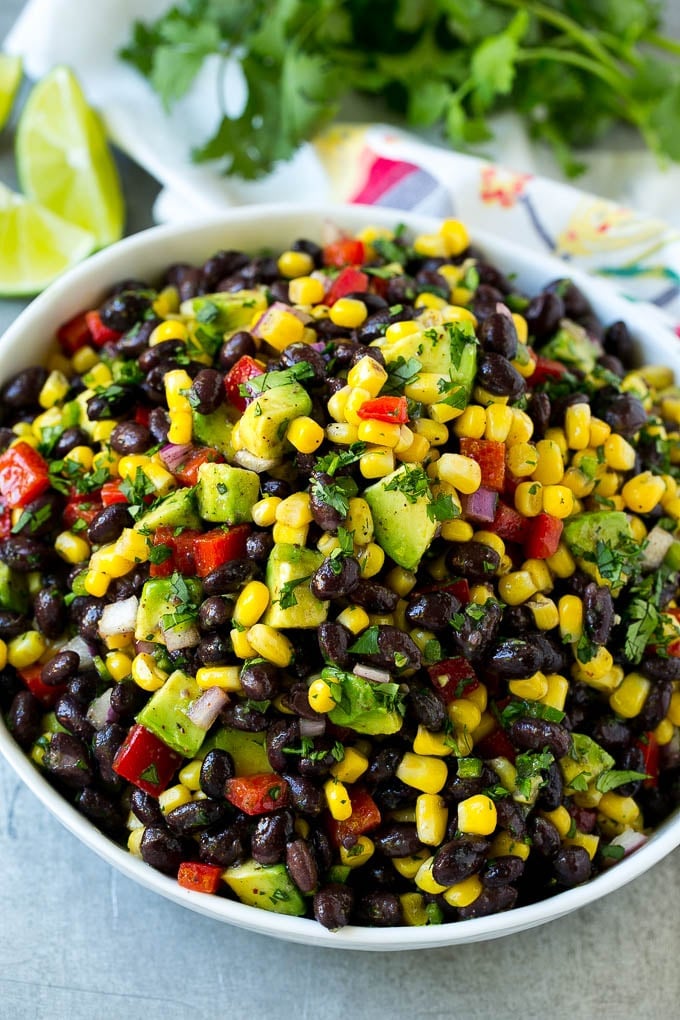 A serving bowl of black bean salad with corn, peppers and avocado.