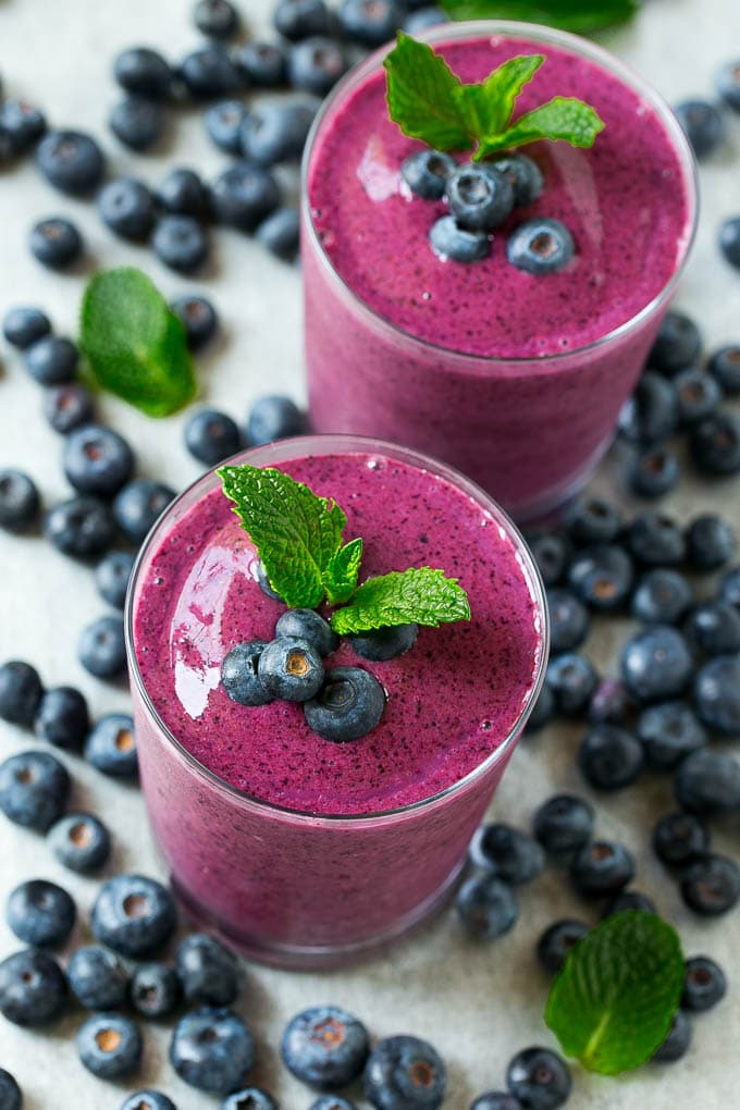 Blueberry smoothies garnished with mint and fresh blueberries.